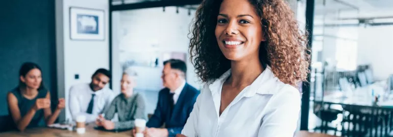 Confident woman in a white shirt smiling at a business meeting.