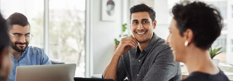 Group of four people smiling during a meeting.