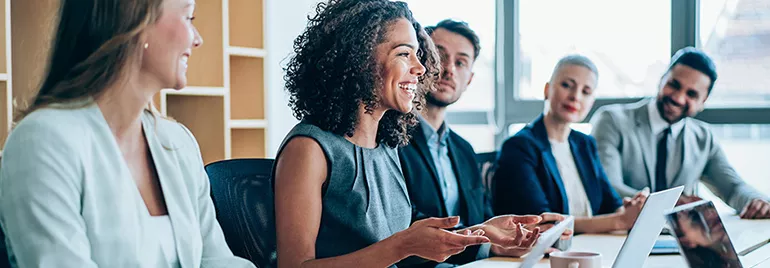 A diverse group of people smiling and talking in a meeting room.