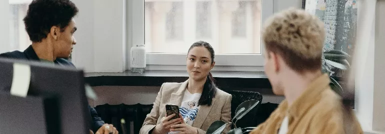 Three people having a discussion in a modern office with plants.