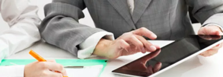 Two business people working on documents and using a tablet.