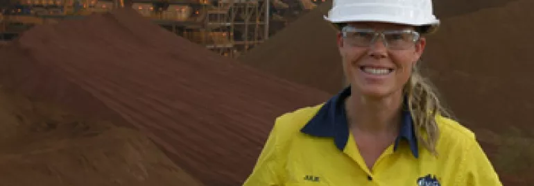 Person in safety gear smiling at a mining site