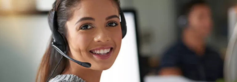 Woman with headset smiling at desk in office