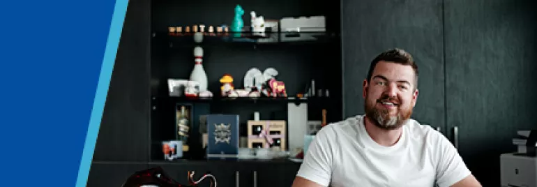 Man sitting at a desk with decorative shelves behind him.