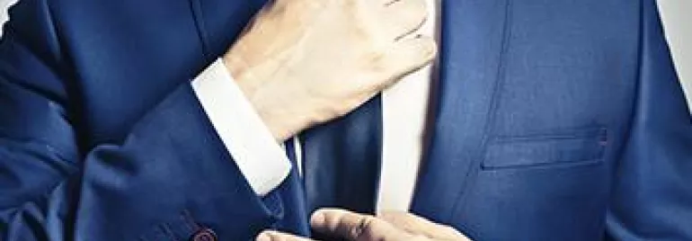 Person in a blue suit adjusting a tie.