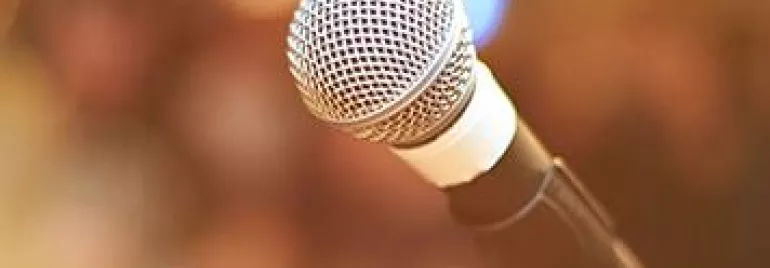 Close-up of a microphone on a stand with a blurred background.
