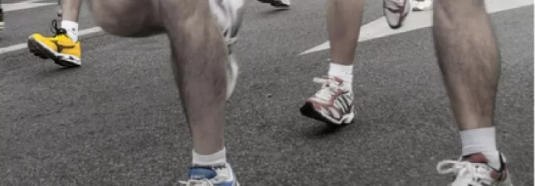 Runners' legs and sneakers on a road during a race.