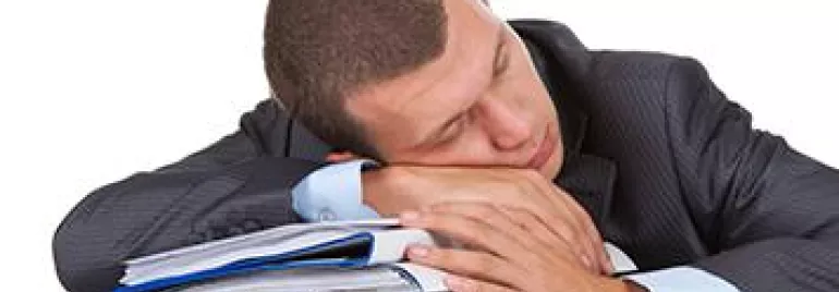 Man in suit sleeping on a pile of documents.