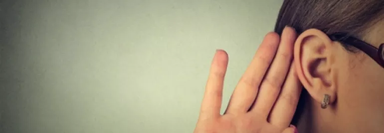Person cupping hand to ear, listening intently.