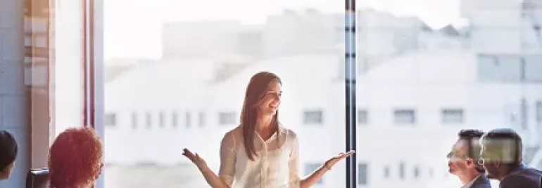 Businesswoman giving a presentation to colleagues in a meeting room.