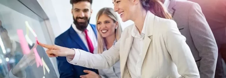 Group of business professionals collaborating with sticky notes on a glass board.
