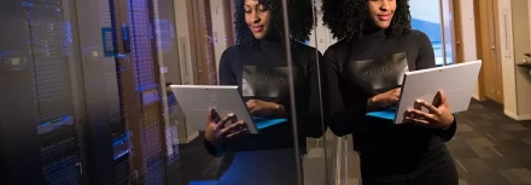Woman in a data center hallway looking at a tablet computer.