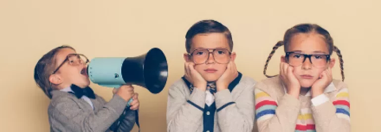 Child with megaphone shouts at bored siblings in glasses.