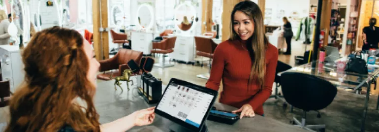Smiling woman at a retail desk assisting a customer in a modern store.