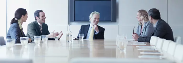 Five business people in a conference room having a discussion.
