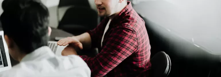 Two people having a conversation at a table in a dimly lit room.