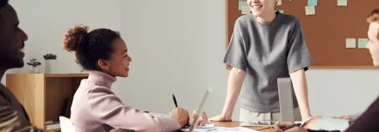 A team having a meeting around a table with laptops and notes.