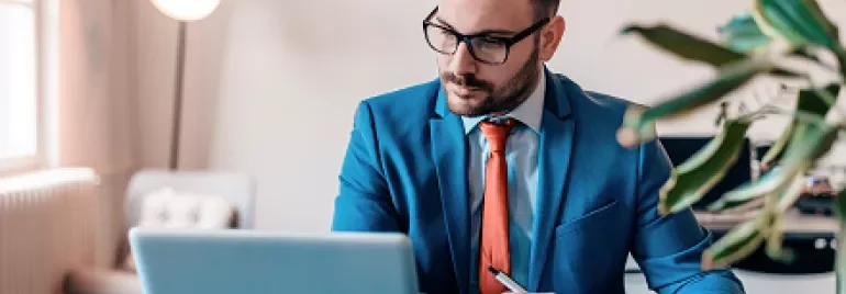 Man in blue suit working on laptop at a desk