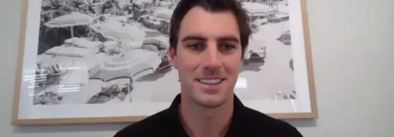 Person smiling in front of a seaside painting in a room.