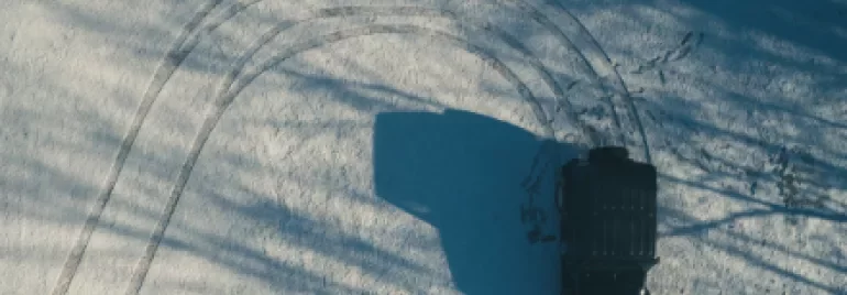 Aerial view of a black vehicle making tire tracks in the snow.