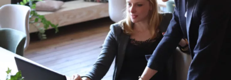 Two women working together on a laptop in an office.