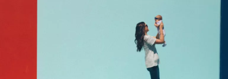 Woman holding baby against a red and blue wall.