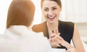 Two women having a friendly and engaging conversation in an office setting.