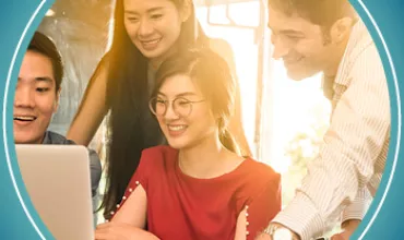 Group of four people smiling and looking at a laptop together.