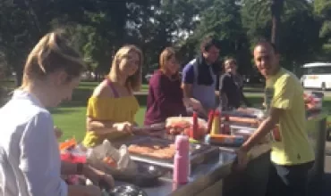 People enjoying a barbecue outside in a park on a sunny day.