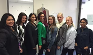 Group of eight people smiling and standing in an office setting.