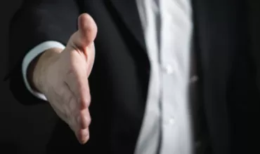 Person in suit extending hand for handshake.