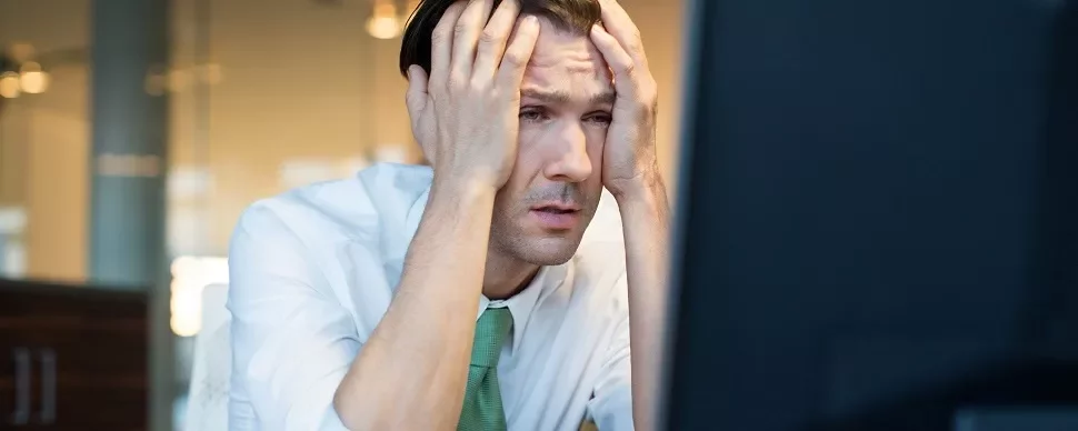 Man in office holding head in frustration