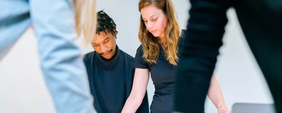 Two people collaborating at a table with focus on documents.