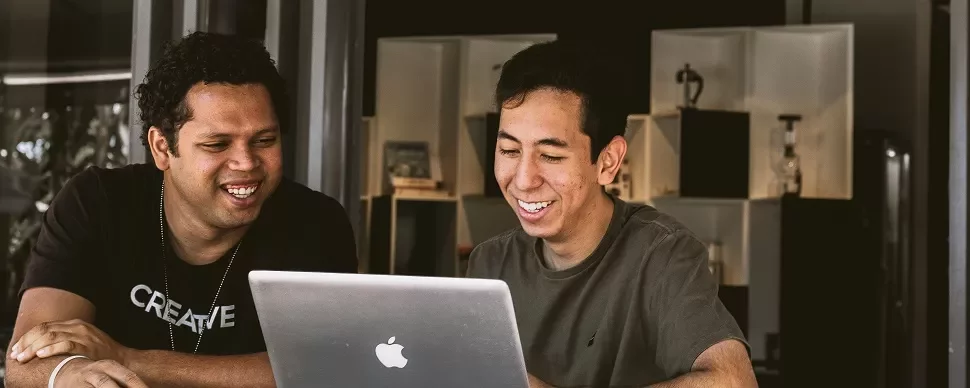 Two people smiling and looking at a laptop screen.