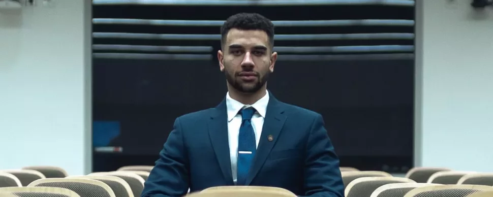 Man in a suit sitting alone in an empty lecture hall.