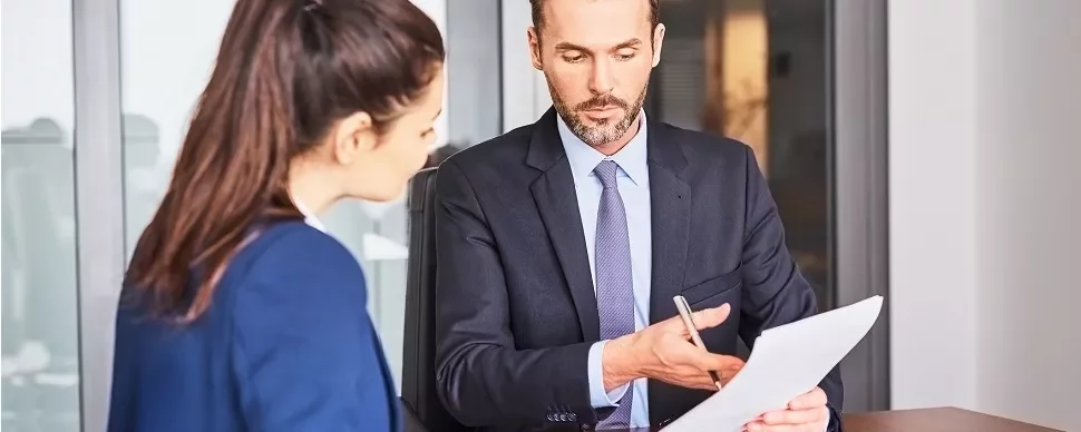 Two professionals reviewing a document in an office setting.