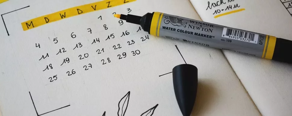 A pen next to a hand-drawn calendar on a notepad.