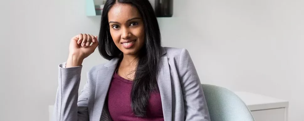 Smiling woman in a gray blazer sitting in a chair.