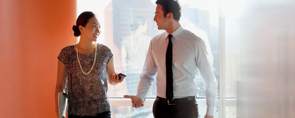 Two professionals walking and talking in a sunlit office