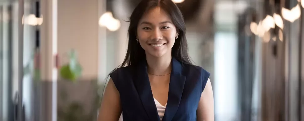 A woman smiling in an office hallway.