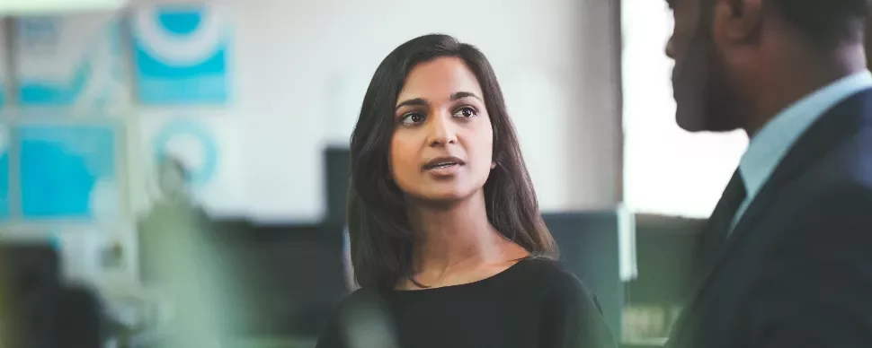 Woman speaking to a man in a business setting.