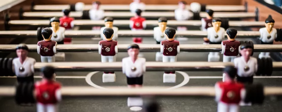 Close-up view of a foosball table with red and white player figures.