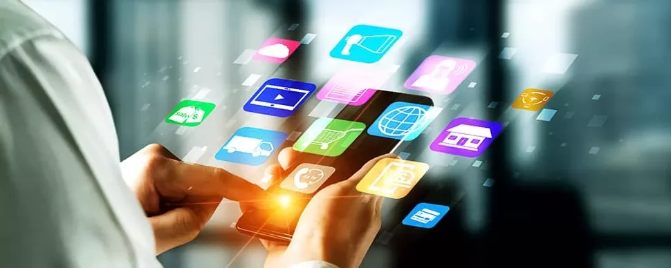 Person using a smartphone with colorful app icons floating above the screen.