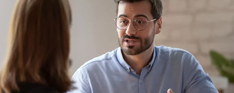 Man with glasses having a conversation with a woman.