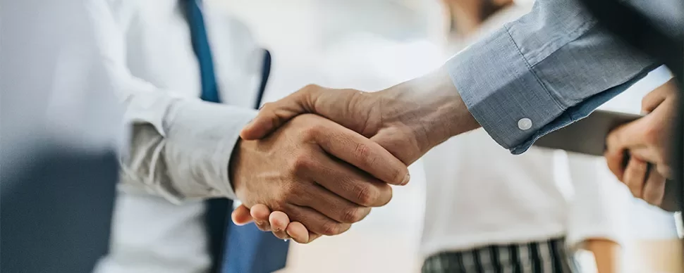 Two people in business attire shaking hands in a close-up view.