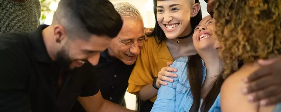 Group of diverse people smiling and hugging each other closely.