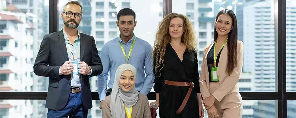 A diverse group of five people smiling in a modern office setting.