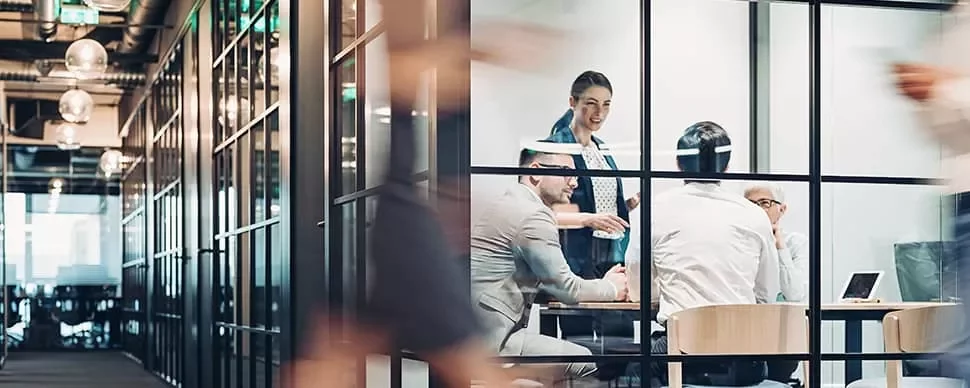 People in a glass-walled conference room having a meeting.