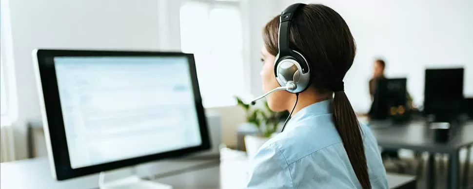 Person in a headset working at a computer in an office.