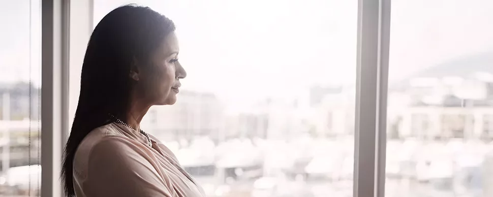 A woman gazing thoughtfully out of a window.
